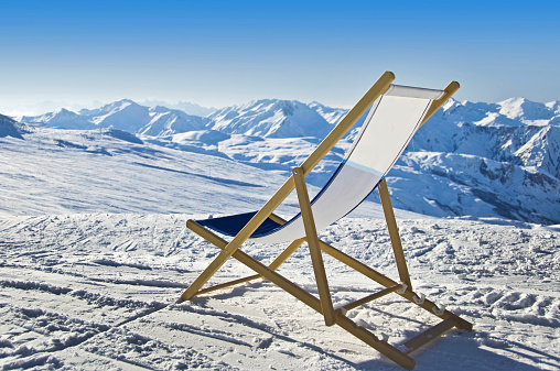 Deckchair in the snow facing the Alps mountains