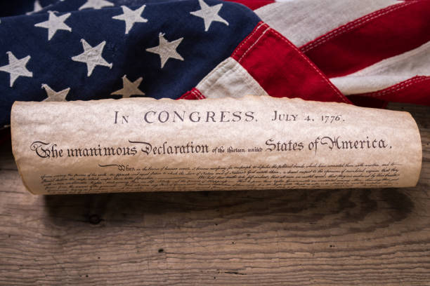 Declaration of Independence on Flag United States Declaration of Independence rolled in a scroll on a vintage American flag and rustic wooden board declaration of independence stock pictures, royalty-free photos & images