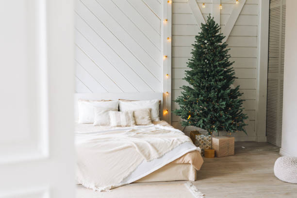 Decorated Christmas tree with the gift boxes from door at bedroom in the bright interior at home stock photo