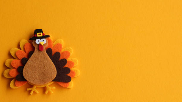 decorated felt turkey on an orange festive background with writing space orange brown and yellow crafted felt turkey wearing pilgrim hat laying flat on an orange background with copy space pilgrim stock pictures, royalty-free photos & images