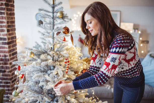 kerstboom versieren - vrouw kerstboom versieren stockfoto's en -beelden