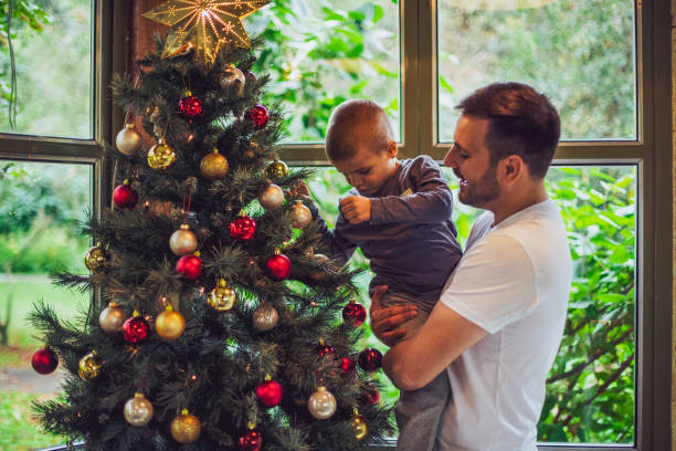 versieren van de kerstboom met papa - vrouw kerstboom versieren stockfoto's en -beelden