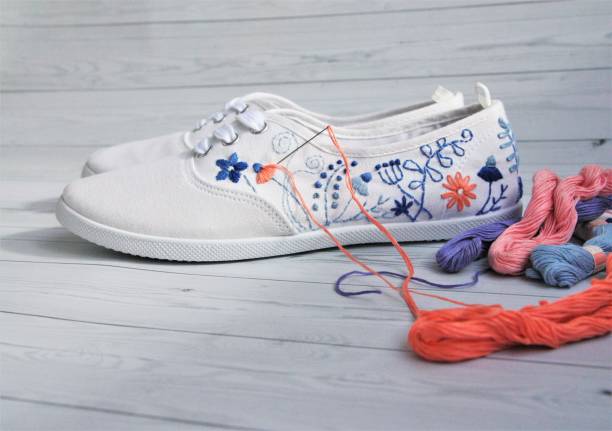 decorating white sneakers with floral embroidery in coral and denim colors stock photo