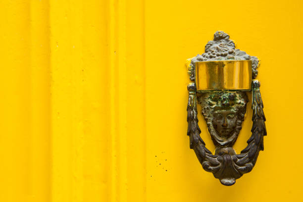 Decorative bronze door handle on a yellow painted door. Malta stock photo