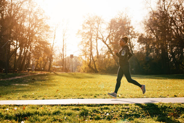 Dedicated African American female athlete running in the park. Full length of black sportswoman jogging in nature. Copy space. jogging stock pictures, royalty-free photos & images