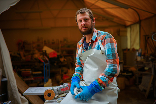 Portrait of a confident male mid-adult stonecutter, at his workshop, while taking a break from work