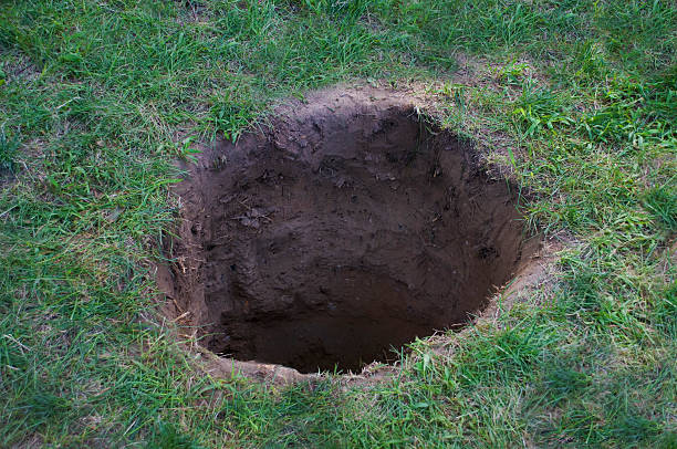 deep dirt hole in ground or lawn - gat stockfoto's en -beelden