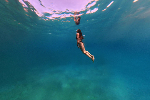 Underwater image of a woman diving in the open sea.