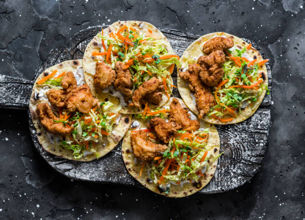 frittierter fisch und coleslaw salat tacos auf einem schneidebrett auf dunklem hintergrund, ansicht von oben - wirsing zubereiten stock-fotos und bilder