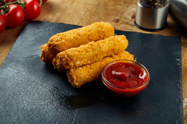 Deep fried mozzarella cheese sticks with red sauce on a black plate. Traditional beer snack. Close up, selective focus stock photo