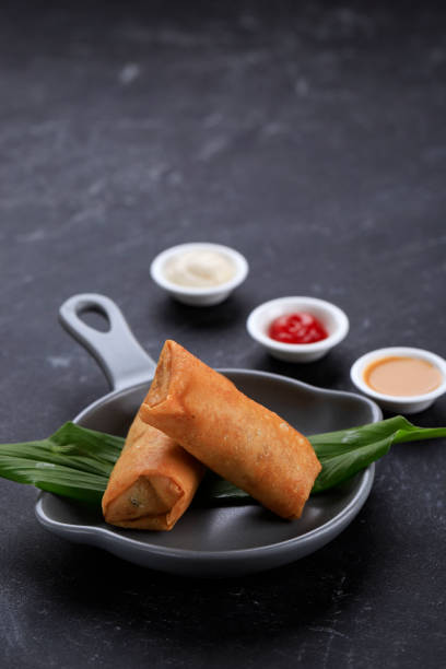 Deep Fried Spring Rolls, Popular as Lumpia or Popia. Served on Grey Pan Plate, Black marble table. Copy Space for Text stock photo