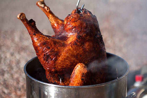 Deep Fried Turkey Hot fresh and delicious turkey being removed from a deep fat fryer after being cooked for a holiday celebration. turkey meat stock pictures, royalty-free photos & images