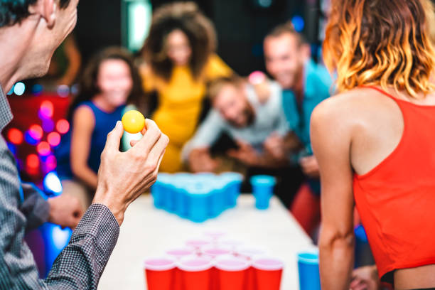 Defocused background of young friends playing beer pong at youth hostel - Free time travel concept with backpackers having genuine fun at guesthouse - Blurred view of happy people on playful attitude stock photo