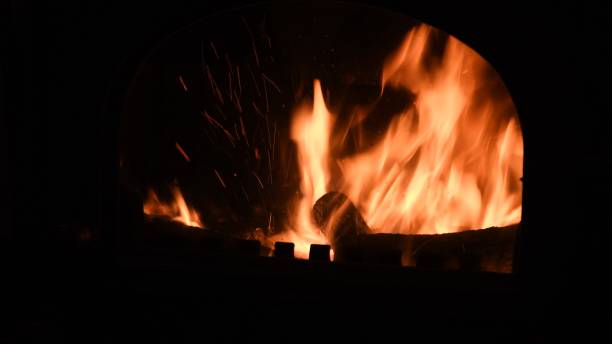 Defocused burning flame with sparks inside rustic furnace stock photo