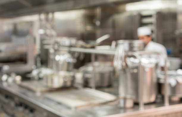 Defocused chef preparing food in commercial kitchen Defocused chef preparing food in commercial stainless steel kitchen in restaurant commercial kitchen stock pictures, royalty-free photos & images