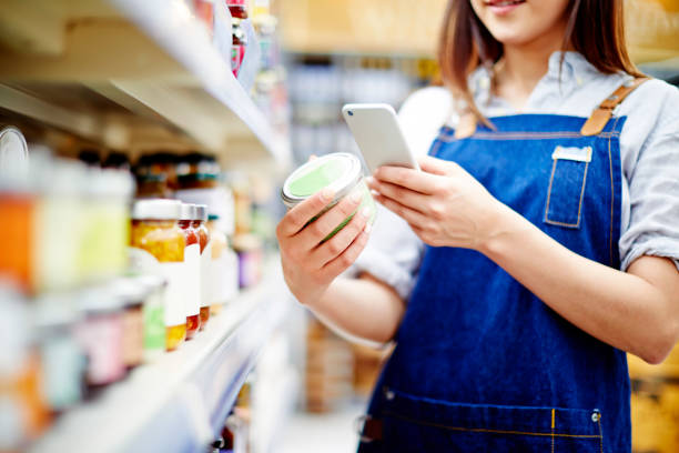 Deli owner scanning label on food container with smart phone stock photo