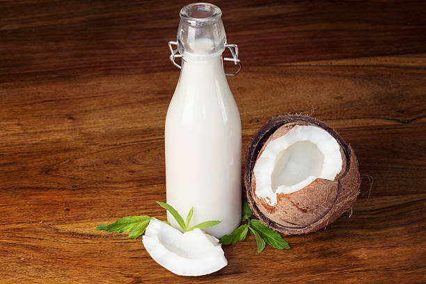 Delicious and Organic Coconut Milk on wooden table Delicious and organic coconut milk on wooden table with mint leaves coconut milk stock pictures, royalty-free photos & images