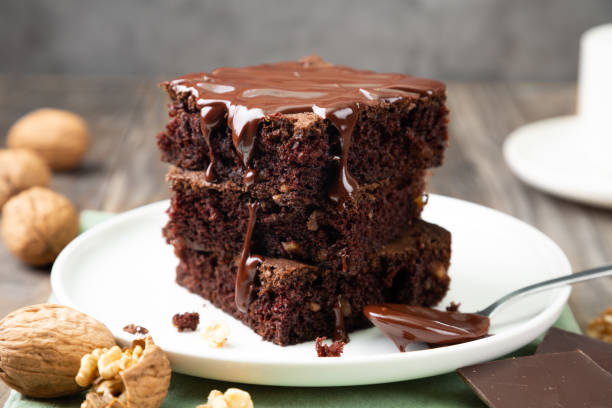 Delicious brownies with melted chocolate on a stack Chocolate spongy brownie cakes with walnuts and melted chocolate topping on a stack baked pastry item stock pictures, royalty-free photos & images