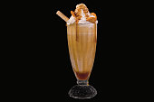 Delicious caramel Milkshake decorated with biscuits in a glass, isolated on black background