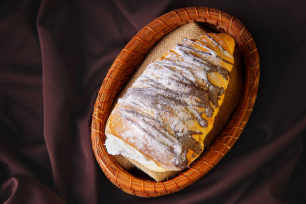 delicious cone-shaped bread rolled up filled with pastry cream covered in homemade chocolate and sugar placed on a rustic container stock photo