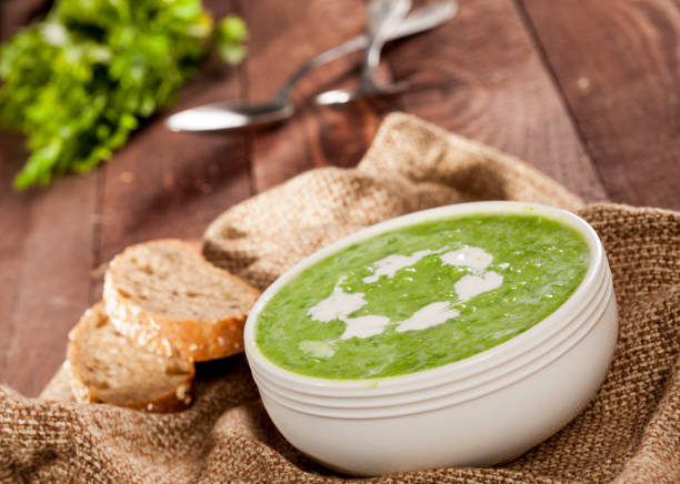 Delicious creamy green vegetable soup with bread close-up on a dark background. stock photo