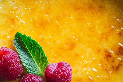 Full frame view of delicious creme brulee raspberries and mint leaf. Close-up of homemade creme brulee.
