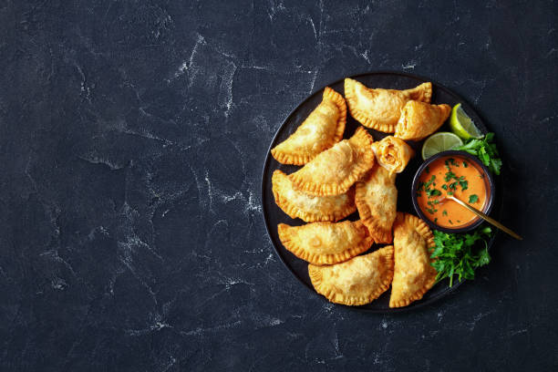 delicious deep-fried empanadas with shredded chicken filling delicious deep fried Buffalo Chicken Empanadas with Low Calorie Dip on a black platter on a concrete table, horizontal view from above, flat lay, free space argentina food stock pictures, royalty-free photos & images