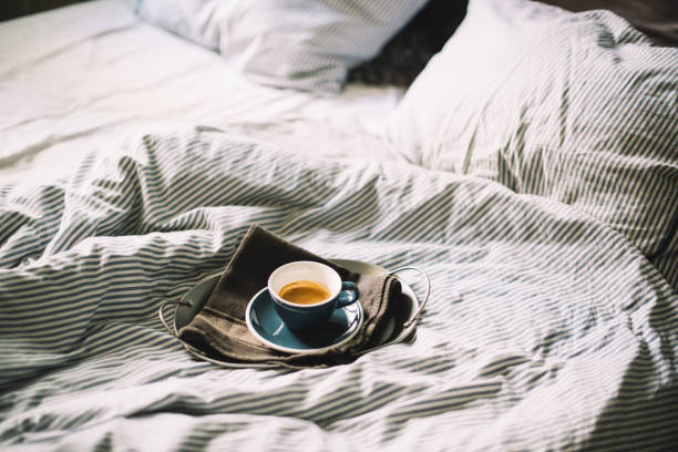 Delicious fresh morning espresso coffee in bed in a ceramic blue cup with a saucer, on the metal tray and black kitchen cloth, morning mood Delicious fresh morning espresso coffee in bed in a ceramic blue cup with a saucer, on the metal tray and black kitchen cloth, morning mood sunday coffee stock pictures, royalty-free photos & images