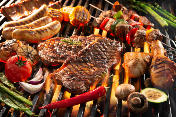 Delicious grilled meat with vegetables sizzling over the coals on barbecue stock photo