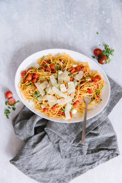 A delicious homemade spaghetti with fresh herbs, cherry tomatoes, and parmesan cheese. stock photo