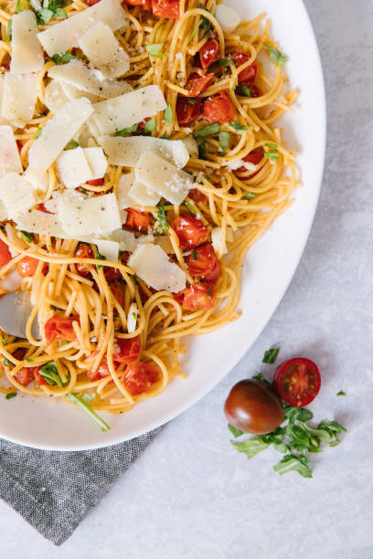 A delicious homemade spaghetti with fresh herbs, cherry tomatoes, and parmesan cheese. stock photo