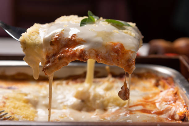 Delicious lasagna made with minced beef bolognese sauce and bechamel sauce topped with basil leaves, soft light stock photo