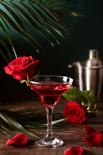 Delicious refreshing beverage drink red cocktail with red rose and petals on wooden table. Romantic, Valentines day concept. stock photo