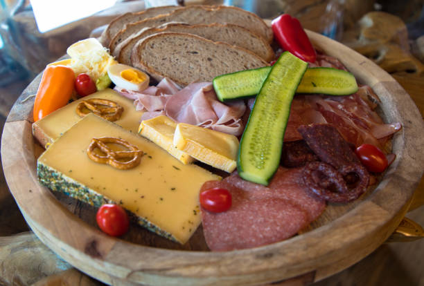 Delicious sausage and cheese plate perfectly garnished and cooked on a wooden board stock photo