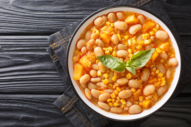 Delicious slow-stewed beans with corn, pumpkin and onions close-up in a bowl. horizontal top view stock photo