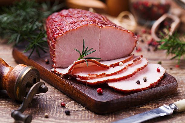 Delicious smoked ham on a wooden board with spices. Delicious smoked ham on a wooden board with spices. ham stock pictures, royalty-free photos & images