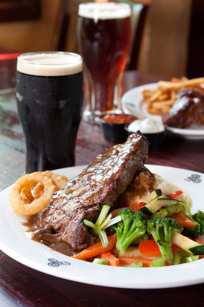 Delicious steak served with vegetables, onion rings and beer stock photo