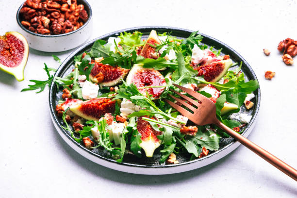 delicious summer salad with sweet  figs, white feta cheese, walnuts, arugula and jam vinegar dressing on white table background, top view, negative space - vegan keto stockfoto's en -beelden