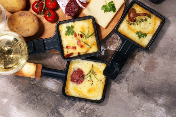 Delicious traditional Swiss melted raclette cheese on diced boiled or baked potato. stock photo