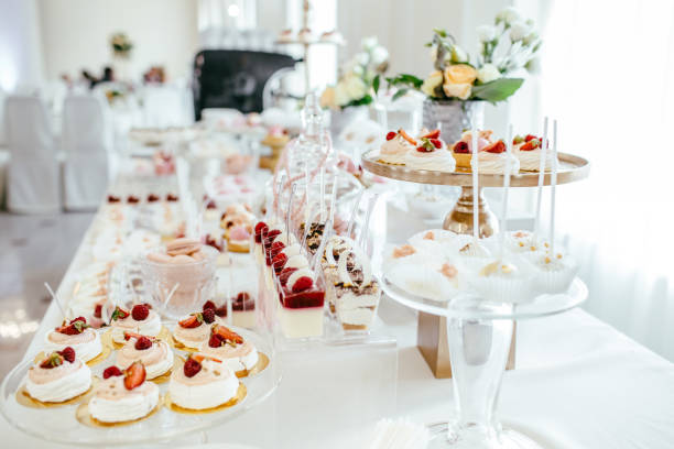 Delicious wedding reception candy bar dessert table full with cakes and sweets and a flower vase with hydrangeas on the background of an exquisite restaurant. stock photo