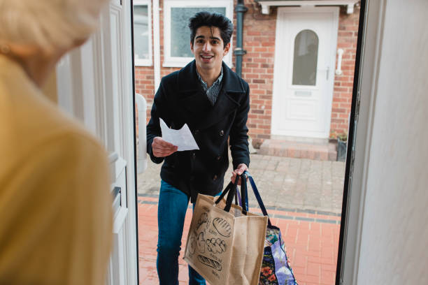 Delivering Groceries to an Elderly Woman Teenage boy is delivering a bag of shopping to an elderly woman at home. worker returning home stock pictures, royalty-free photos & images