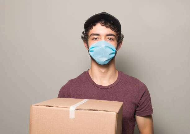 delivery boy wearing face mask stock photo