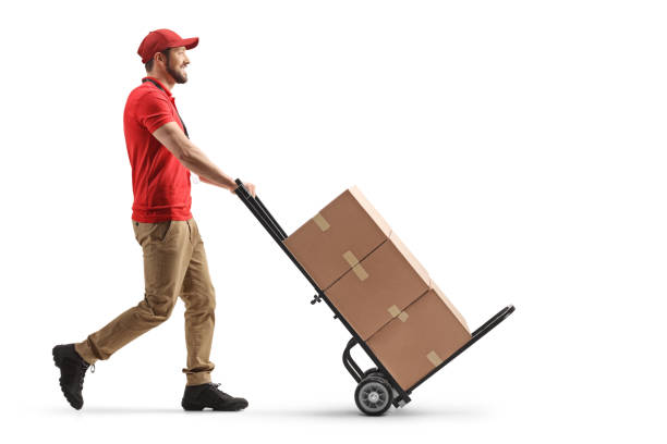 Delivery man pushing a hand truck with cardboard boxes stock photo