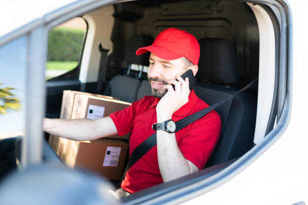 Delivery person contacting a customer while driving stock photo