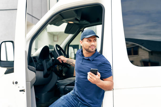 Delivery person with mobile phone gets out of the car stock photo