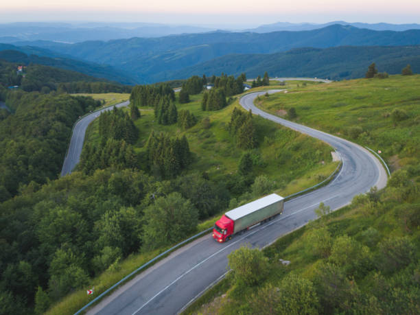 leveranslastbil med last kör på skogsväg i bergen vid solnedgången. - european highway drone bildbanksfoton och bilder