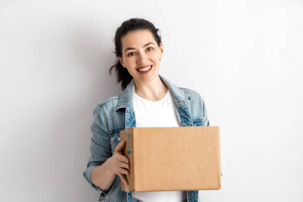 Delivery woman holding cardboard box stock photo