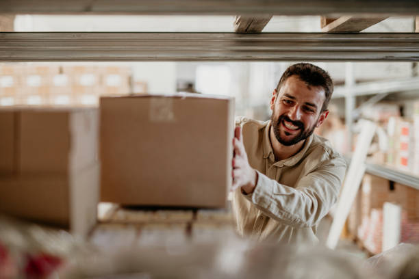 Delivery worker putting a cardboard box on a shelf stock photo