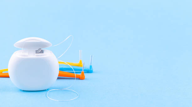 Dental floss and interdental brush angles on blue background, copy space stock photo