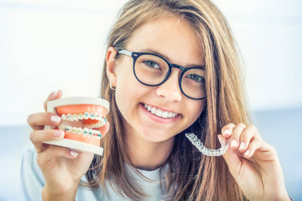 Dental invisible braces or silicone trainer in the hands of a young smiling girl. Orthodontic concept - Invisalign. stock photo